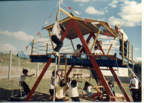 Crianças brincam em casinha colorida de madeira com balança no primeiro parque do Colégio Uirapuru