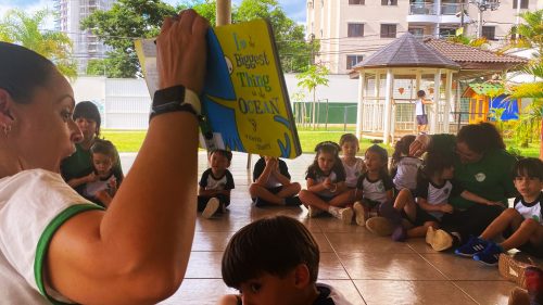 Professora lê livro em inglês com crianças em roda